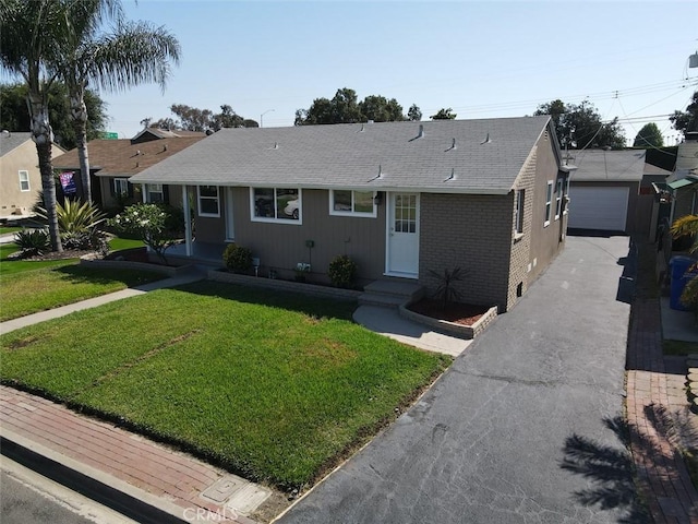 single story home featuring a garage, an outbuilding, and a front lawn