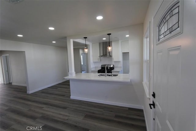 kitchen with wall chimney range hood, sink, dark hardwood / wood-style floors, decorative light fixtures, and kitchen peninsula