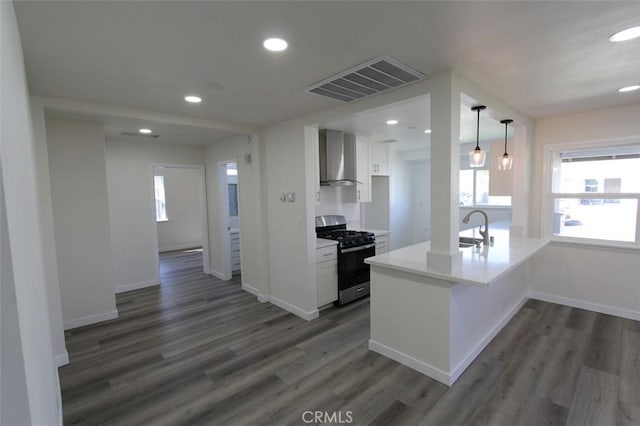 kitchen with gas range, white cabinetry, wall chimney exhaust hood, dark hardwood / wood-style flooring, and kitchen peninsula