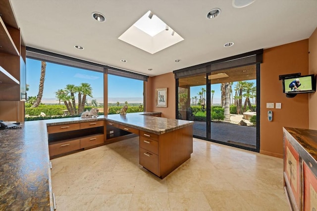 kitchen featuring a skylight, expansive windows, and dark stone counters