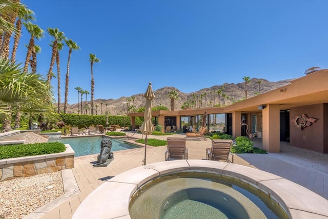 view of pool with an in ground hot tub, a mountain view, and a patio