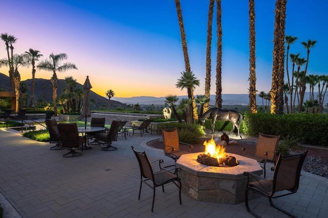 patio terrace at dusk with a fire pit and a mountain view