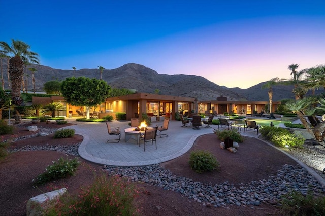 back house at dusk featuring a patio area, a mountain view, and a fire pit