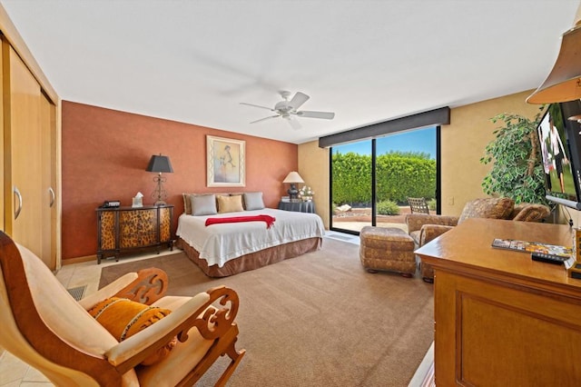 bedroom featuring access to exterior, ceiling fan, light tile patterned floors, a wall of windows, and a closet