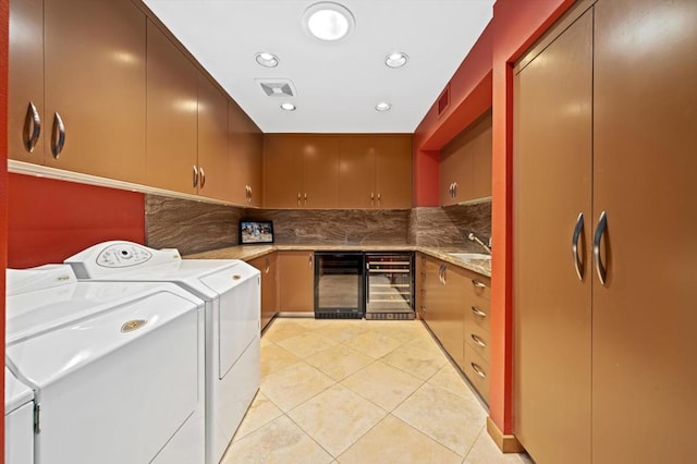 clothes washing area featuring washer and clothes dryer, light tile patterned flooring, cabinets, and beverage cooler