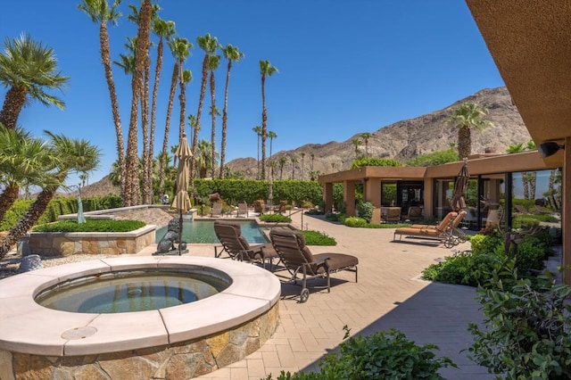 view of patio featuring a mountain view and a pool with hot tub