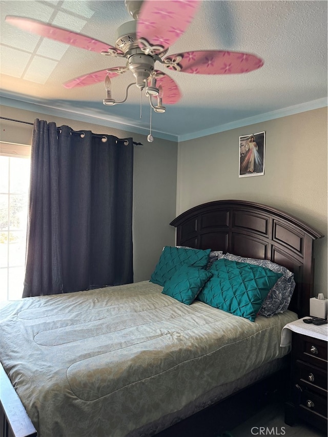 bedroom featuring ceiling fan, crown molding, and a textured ceiling