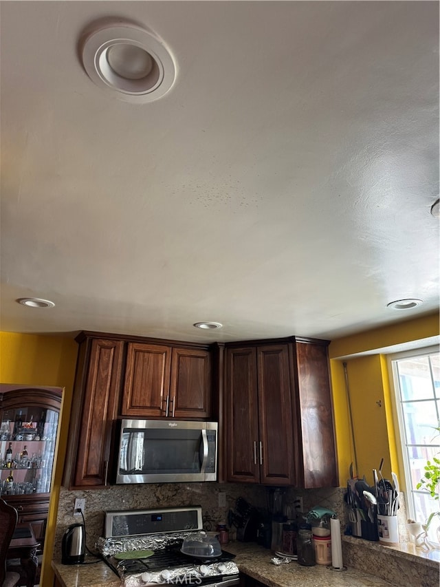 kitchen featuring dark brown cabinetry, tasteful backsplash, and stove