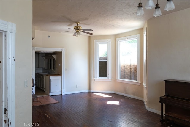 living room with ceiling fan, dark wood-type flooring, and a textured ceiling