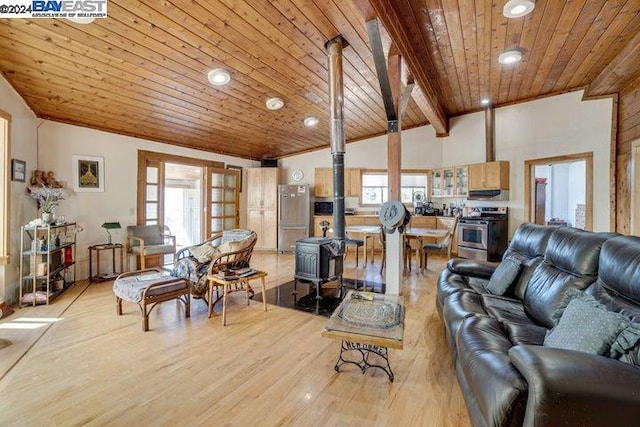 living room with wood ceiling, lofted ceiling with beams, a wood stove, and plenty of natural light