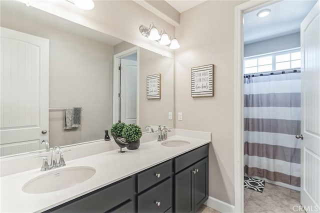 full bathroom with double vanity, a shower with curtain, baseboards, and a sink