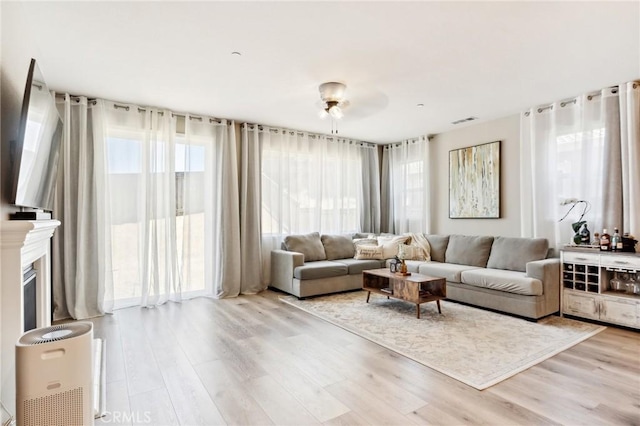 living room with a glass covered fireplace, visible vents, and wood finished floors