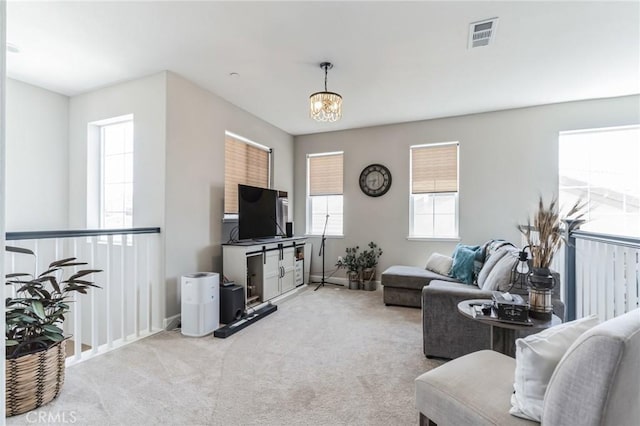 living area with an inviting chandelier, visible vents, and light colored carpet