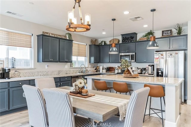 kitchen with appliances with stainless steel finishes, visible vents, a kitchen island, and a kitchen bar