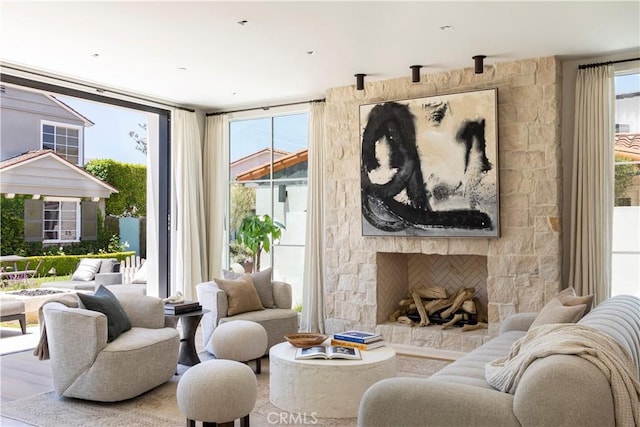 living room featuring hardwood / wood-style floors, a stone fireplace, and expansive windows