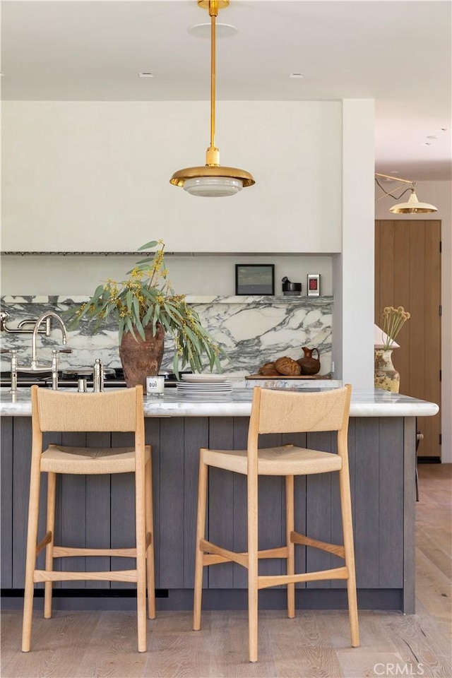 kitchen with a kitchen bar, light hardwood / wood-style flooring, and hanging light fixtures