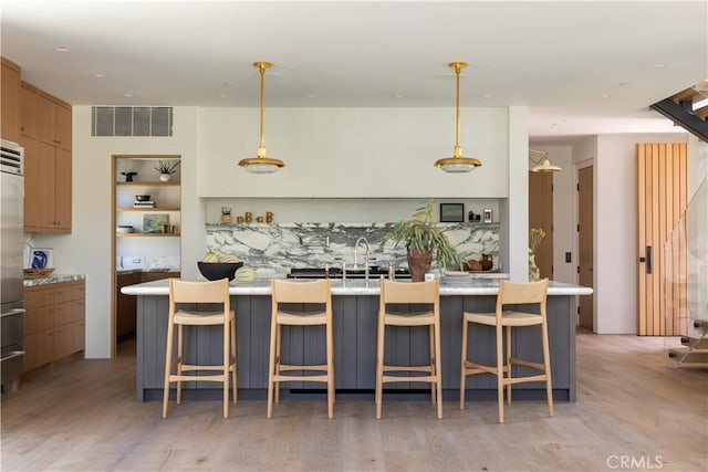 kitchen featuring a kitchen bar, a kitchen island, pendant lighting, and light wood-type flooring