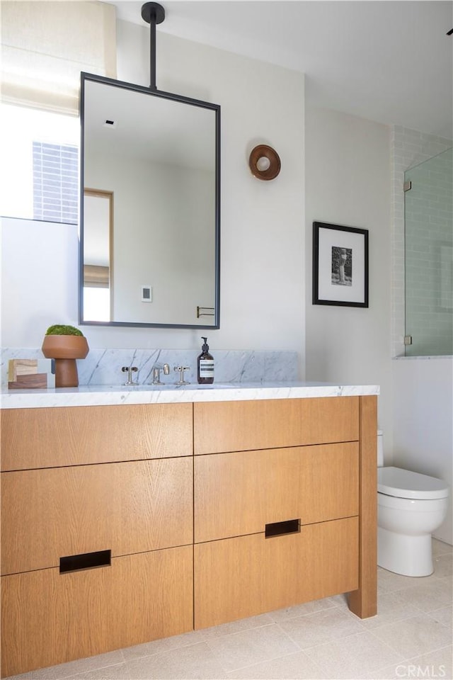 bathroom featuring tile patterned flooring, a shower with door, vanity, and toilet