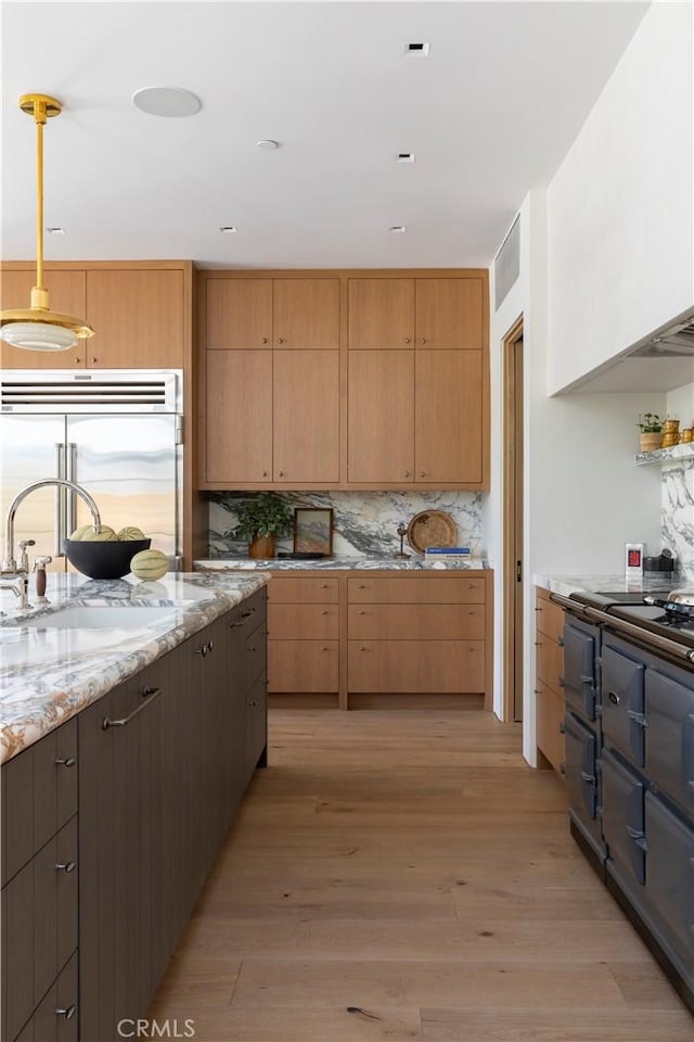 kitchen with sink, light hardwood / wood-style flooring, pendant lighting, and appliances with stainless steel finishes