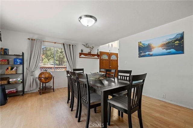 dining area featuring light wood finished floors and baseboards