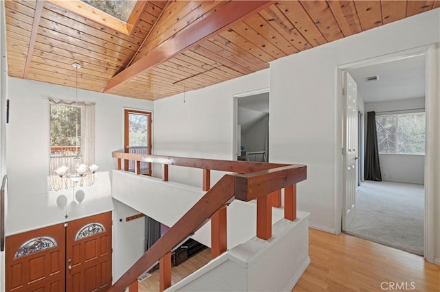 hallway with a healthy amount of sunlight, wooden ceiling, and an upstairs landing
