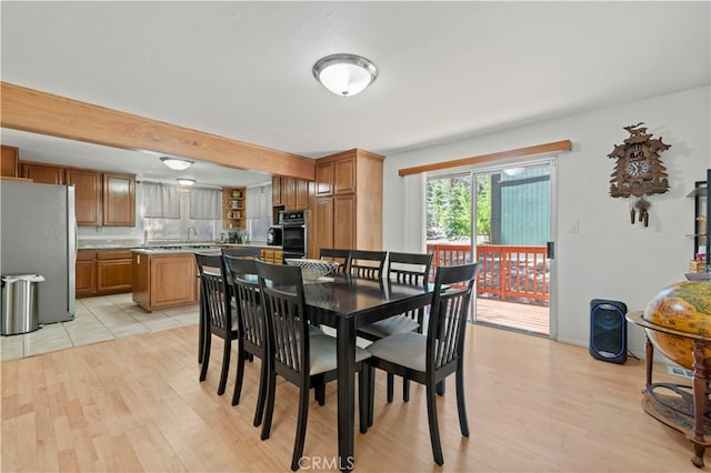 dining space featuring light wood-type flooring and beam ceiling