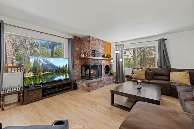 living room with a brick fireplace and light hardwood / wood-style flooring