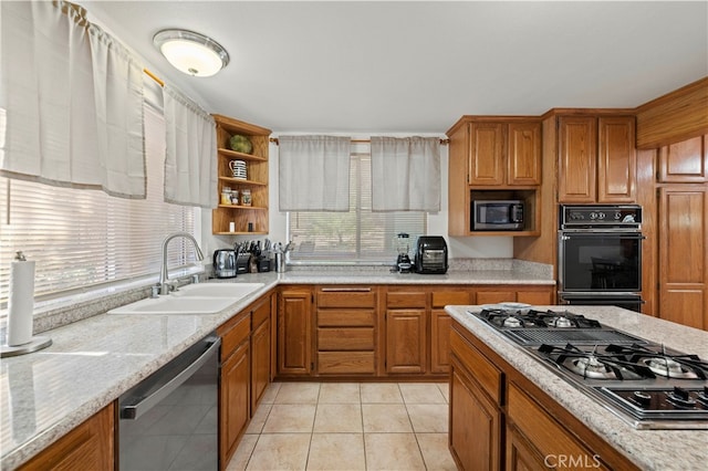 kitchen with light stone counters, light tile patterned flooring, stainless steel appliances, and sink