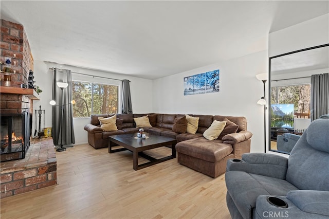 living room featuring a brick fireplace and light hardwood / wood-style flooring