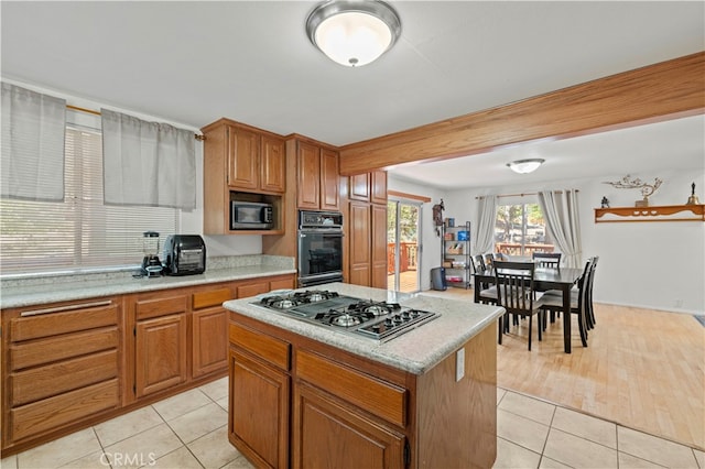 kitchen with appliances with stainless steel finishes, light hardwood / wood-style floors, and a center island