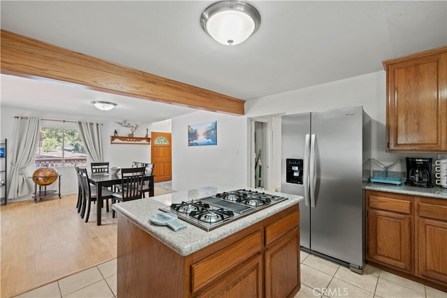 kitchen with light stone countertops, appliances with stainless steel finishes, light wood-type flooring, and a center island