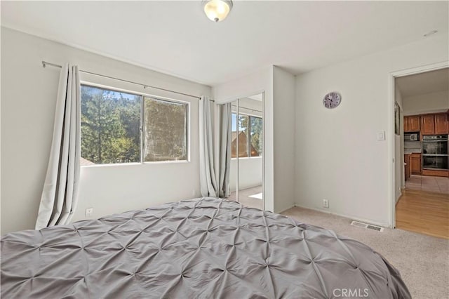 unfurnished bedroom with a closet, light carpet, and visible vents