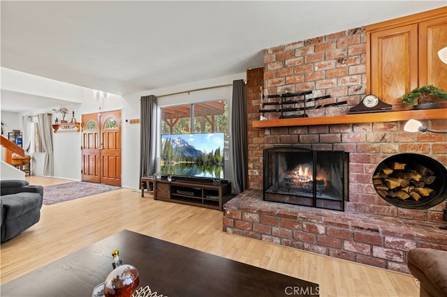 living room with a brick fireplace and hardwood / wood-style floors