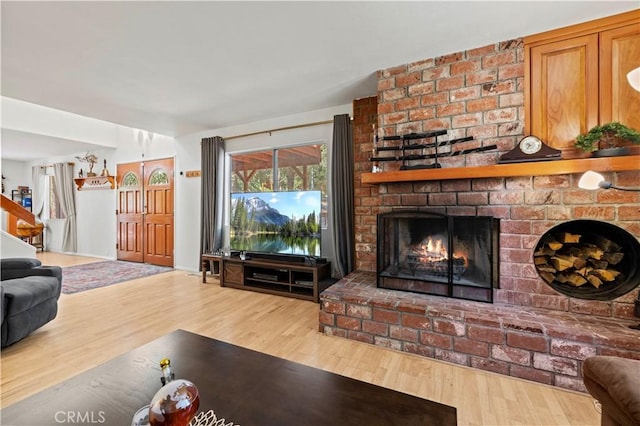 living room with a brick fireplace and wood finished floors