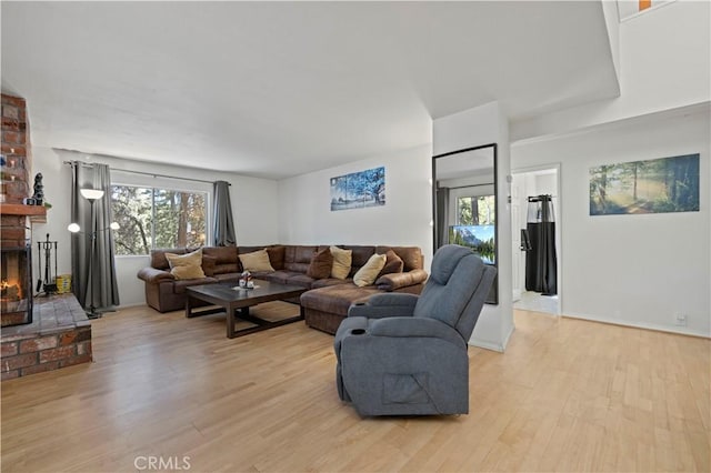 living room featuring a fireplace, light wood-style floors, and plenty of natural light