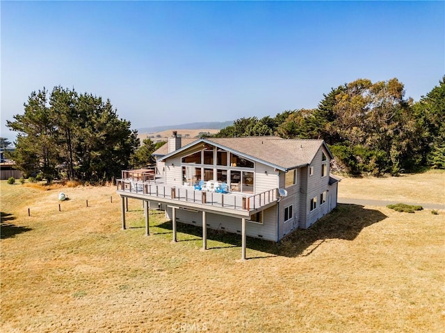 rear view of house featuring a wooden deck and a yard