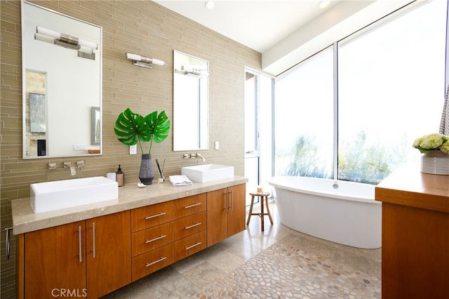 bathroom with backsplash, tile walls, vanity, and a bathtub