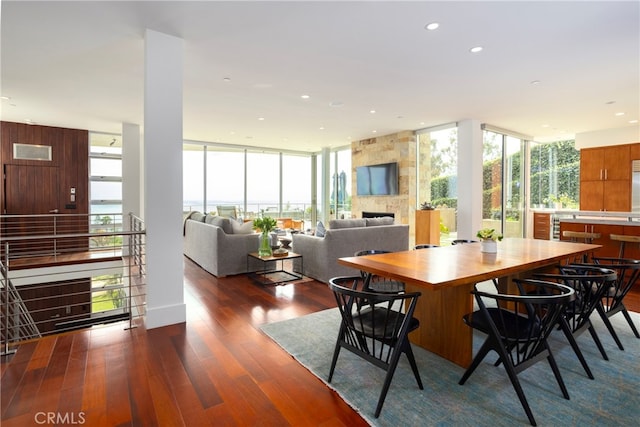 dining space featuring floor to ceiling windows, dark hardwood / wood-style flooring, and a fireplace