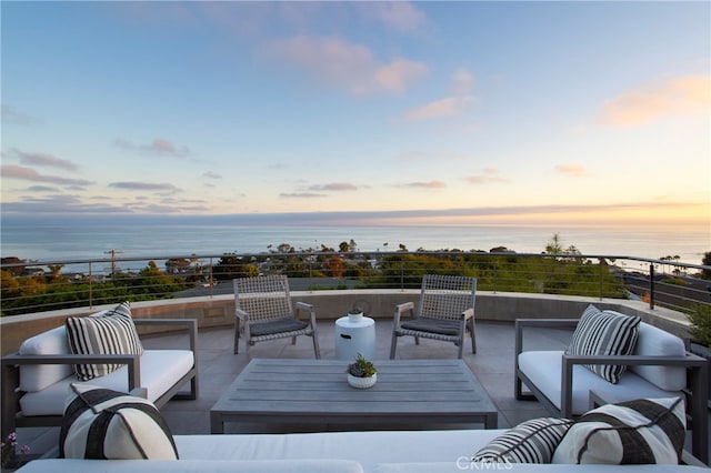 deck at dusk with an outdoor living space and a water view