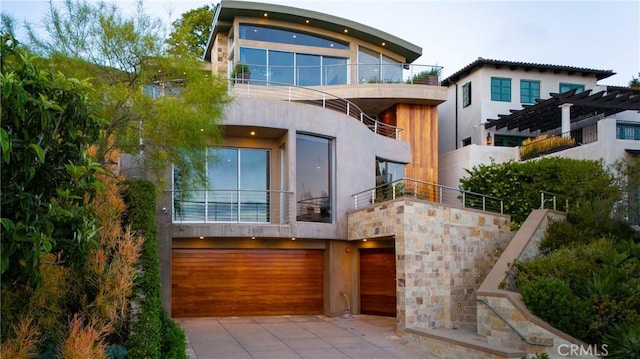 view of front of house featuring driveway, a garage, stucco siding, and a balcony