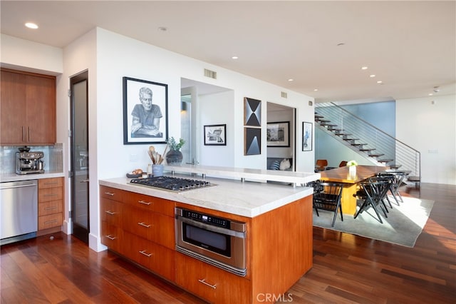 kitchen with kitchen peninsula, decorative backsplash, dark hardwood / wood-style floors, and appliances with stainless steel finishes