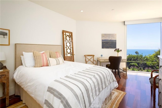 bedroom with hardwood / wood-style flooring and a water view