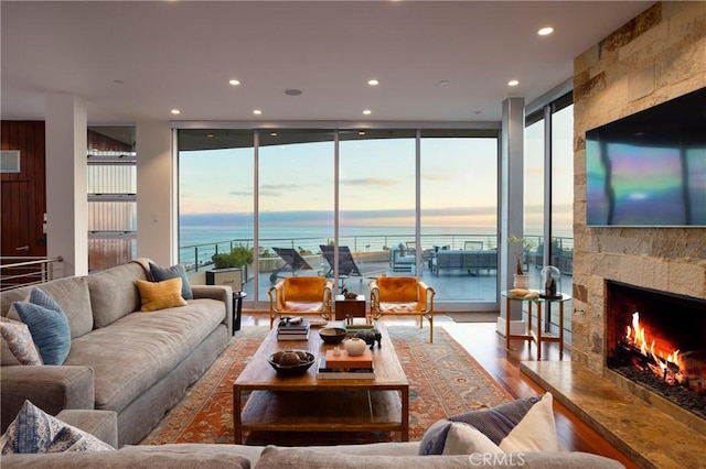 living area featuring recessed lighting, a wall of windows, a fireplace, and wood finished floors