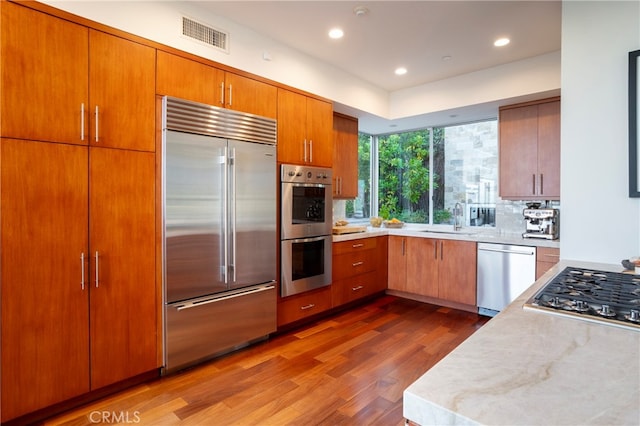 kitchen featuring sink, decorative backsplash, appliances with stainless steel finishes, and dark hardwood / wood-style flooring