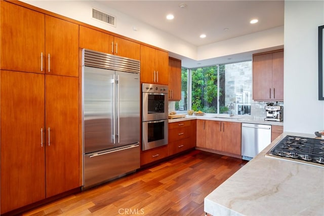 kitchen with light countertops, stainless steel appliances, a sink, visible vents, and wood finished floors