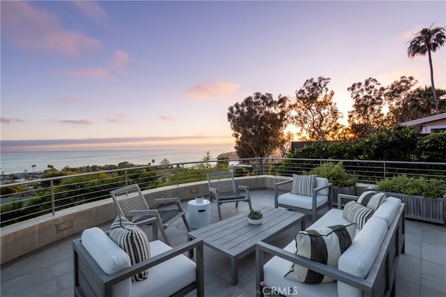 patio terrace at dusk with a balcony, a water view, and an outdoor hangout area