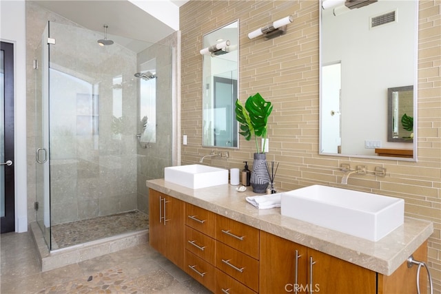 bathroom featuring a shower with shower door, tile walls, vanity, and tasteful backsplash