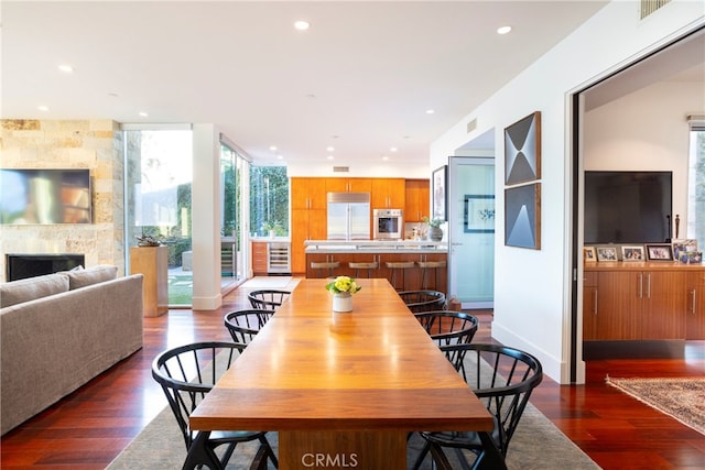 dining space with a tile fireplace, dark hardwood / wood-style floors, and expansive windows