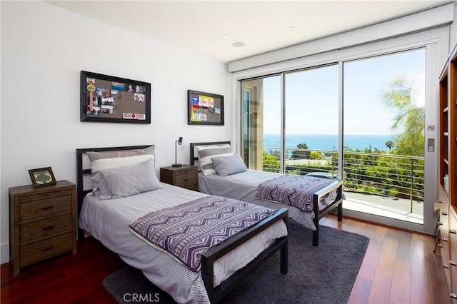 bedroom with dark wood-type flooring, access to exterior, and a water view