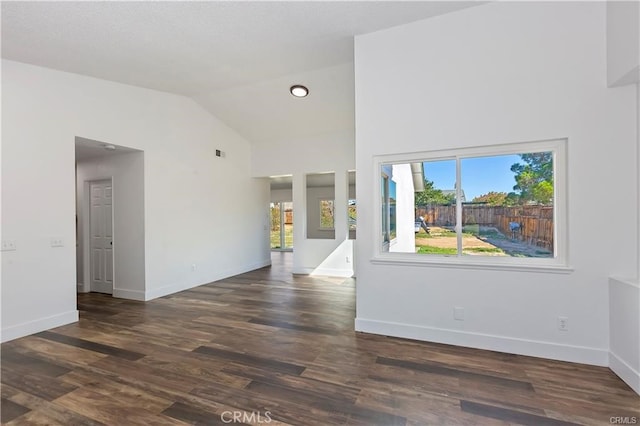 spare room with dark wood-type flooring and vaulted ceiling